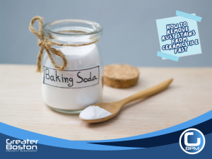 Glass jar of baking soda with wooden spoon for DIY rust stain removal on ceramic tile
