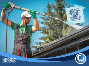 Worker cleaning gutters with a pressure washer during roof maintenance to prevent water leaks