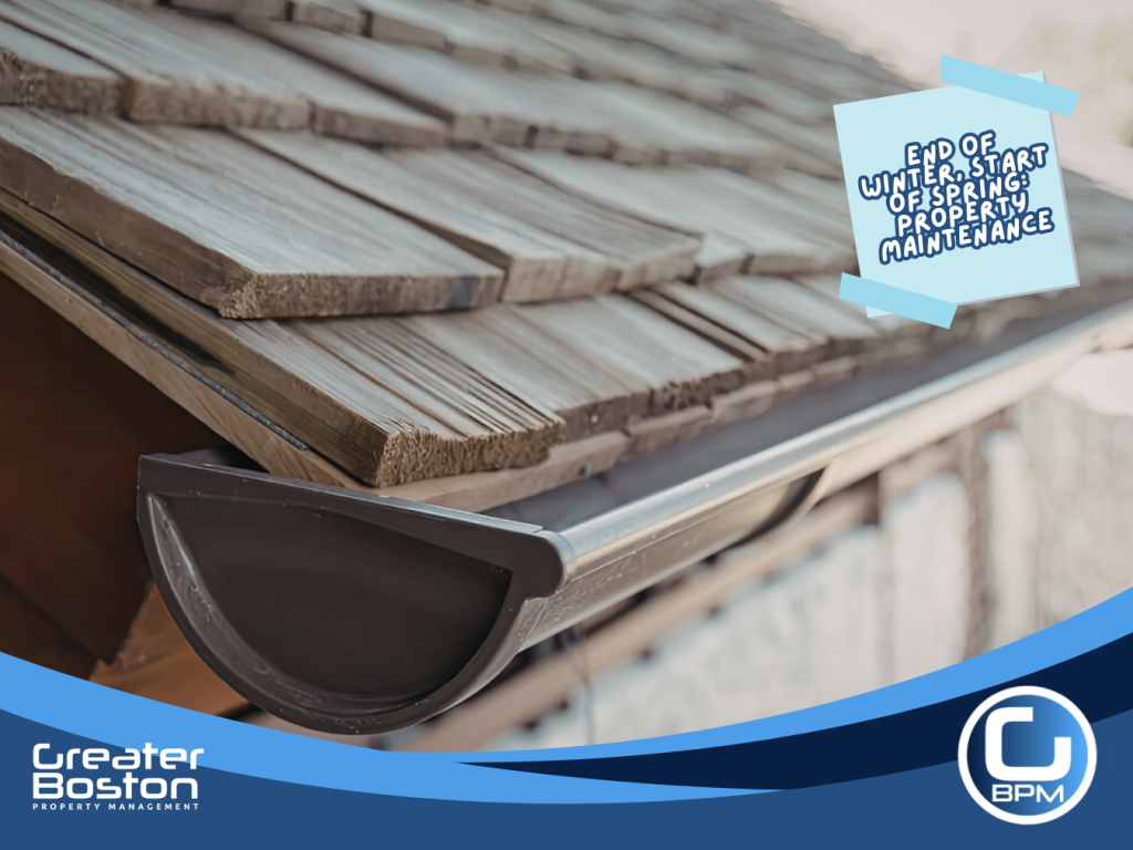 Close-up of roof shingles and gutter system being inspected for winter damage during spring property maintenance.