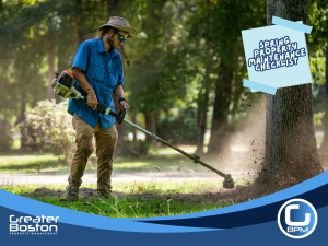 Landscaper using a string trimmer to maintain yard during spring property maintenance for rental property.