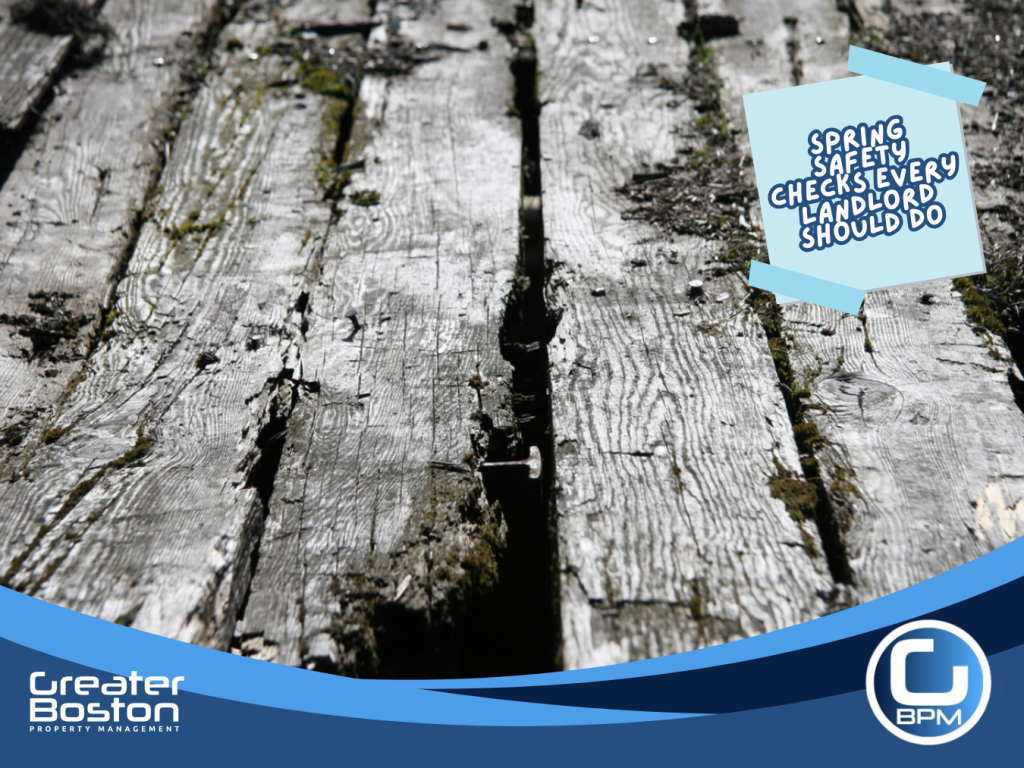 Rotting and cracked wooden deck boards showing structural damage during spring safety inspection for rental property.