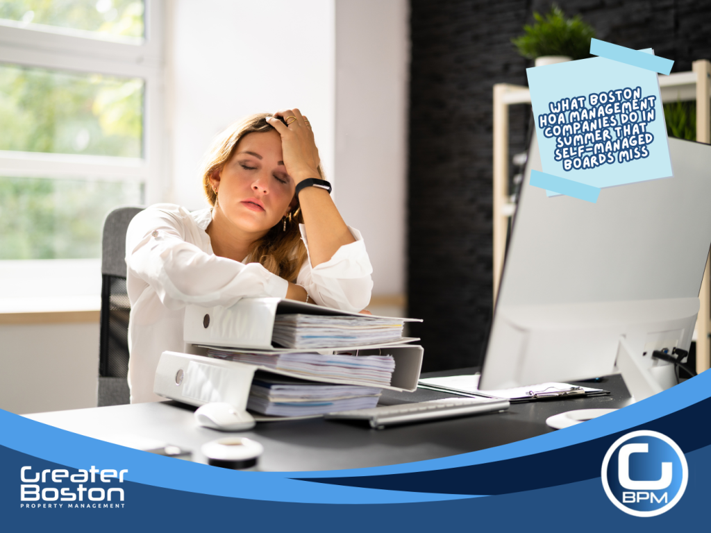 Exhausted self-managed Boston HOA board member slumped over stacks of binders and paperwork representing the compliance gaps and missed summer tasks that overwhelm self-managed associations in 2026